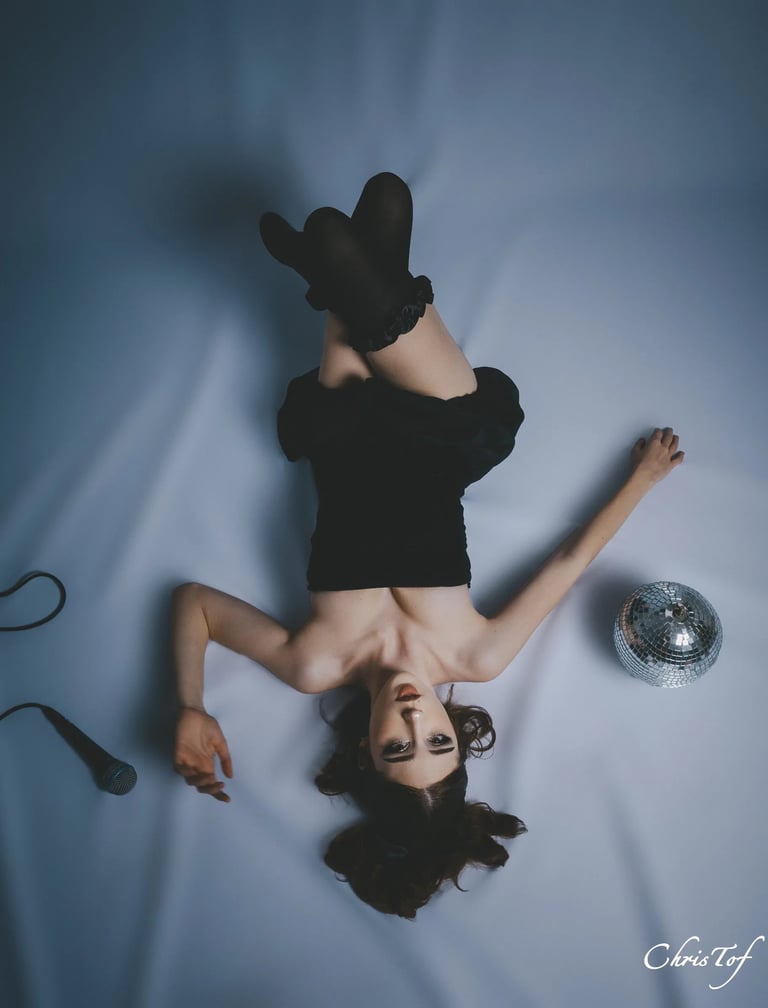 Shooting femme en robe noire allongée tête en bas avec un micro et une boule à facettes à perpignan 