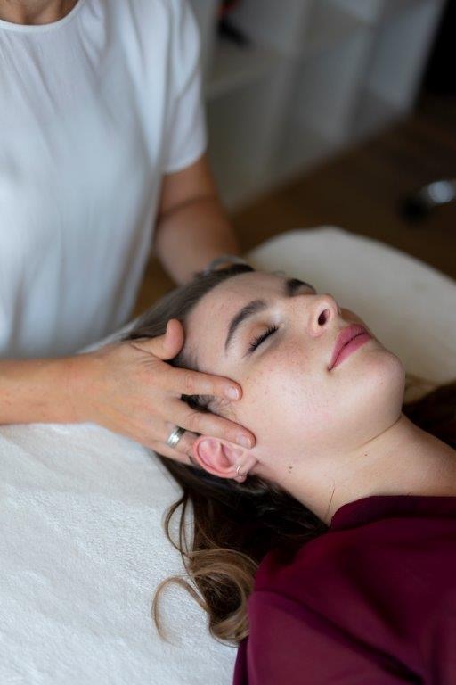 Hannelore Freischlager legt die Hände auf den Kopf der Person auf der Liege auf