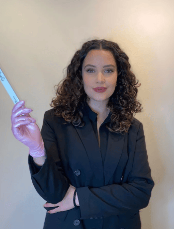 a woman in a black suit and gloves holding a toothbrush