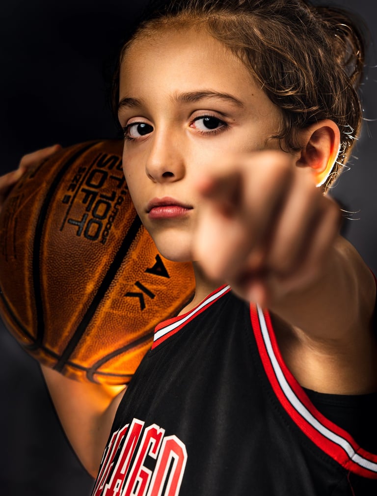 a young boy holding a basketball ball and pointing at the camera