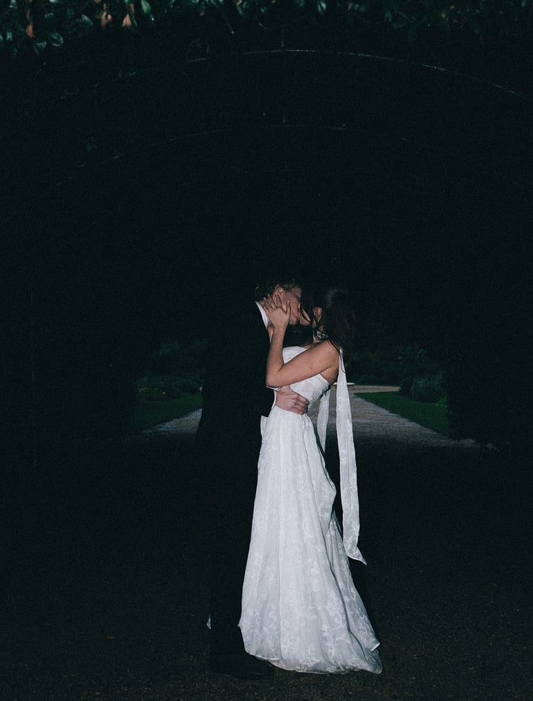 A bride and groom sharing a romantic kiss at a dark night wedding ceremony outdoors.