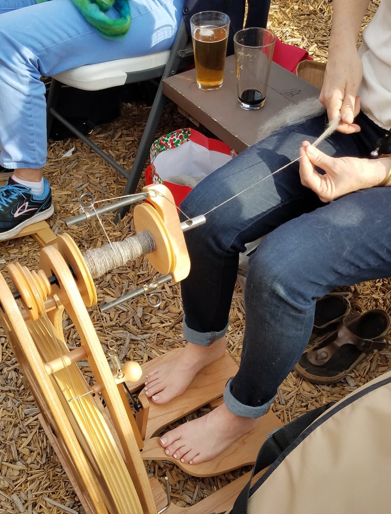 A close-up of someone spinning thread on a spinning wheel while attending First Magnitude Brewery.