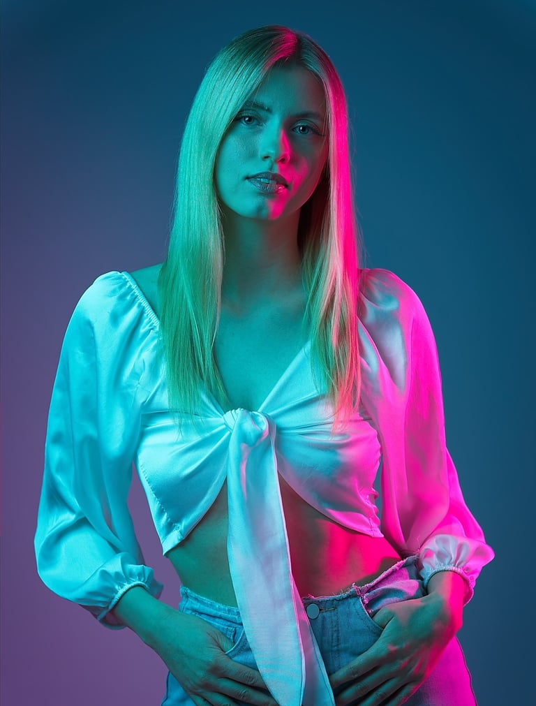 Portrait einer Frau mit weißer Bluse und Jeans vor farbig beleuchtetem Hintergrund