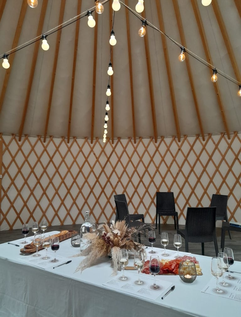 Wine tasting event setup inside a cozy yurt with string lights and charcuterie boards.