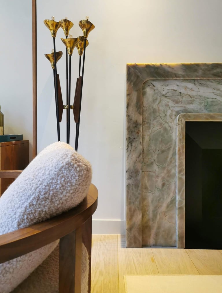 Modern luxury living room with a marble fireplace, gold floor lamp, and cozy bouclé armchair.