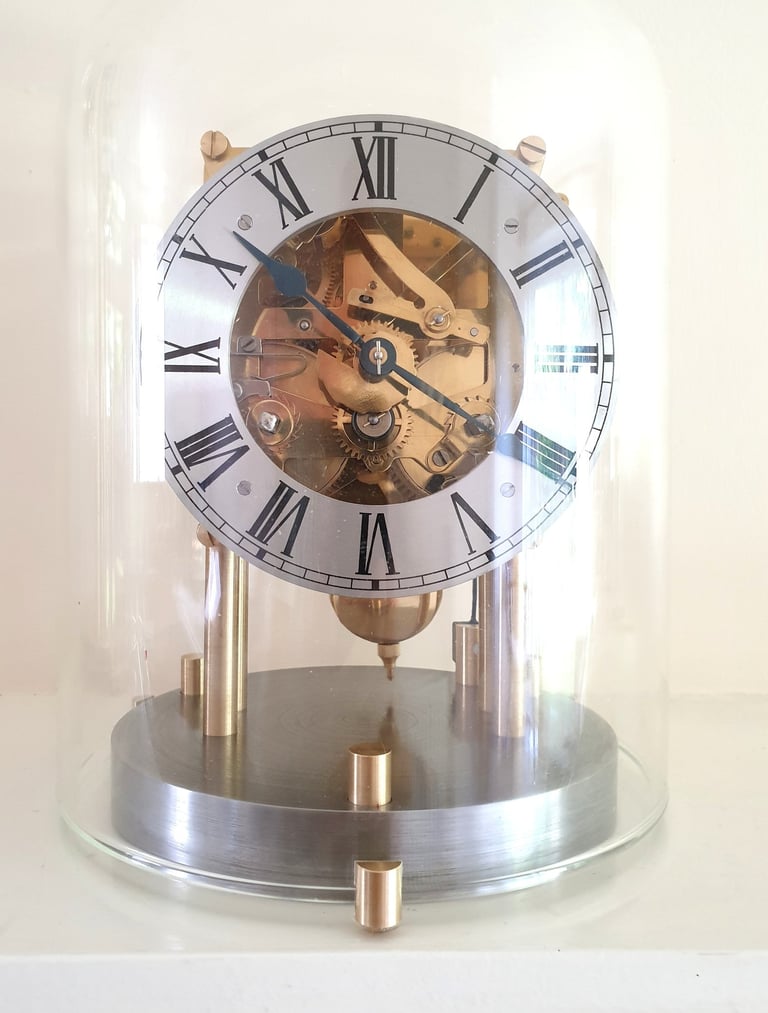 Mantel clock movement with roman numerals and glass dome.