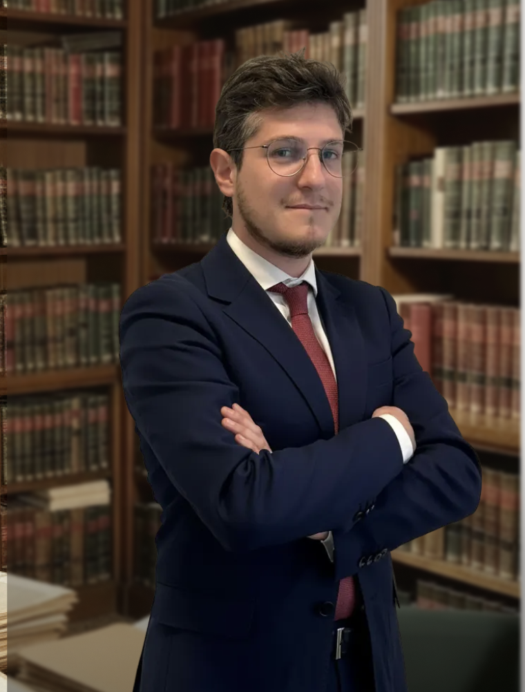 Professional male lawyer in a navy blue suit standing in a legal library with books.