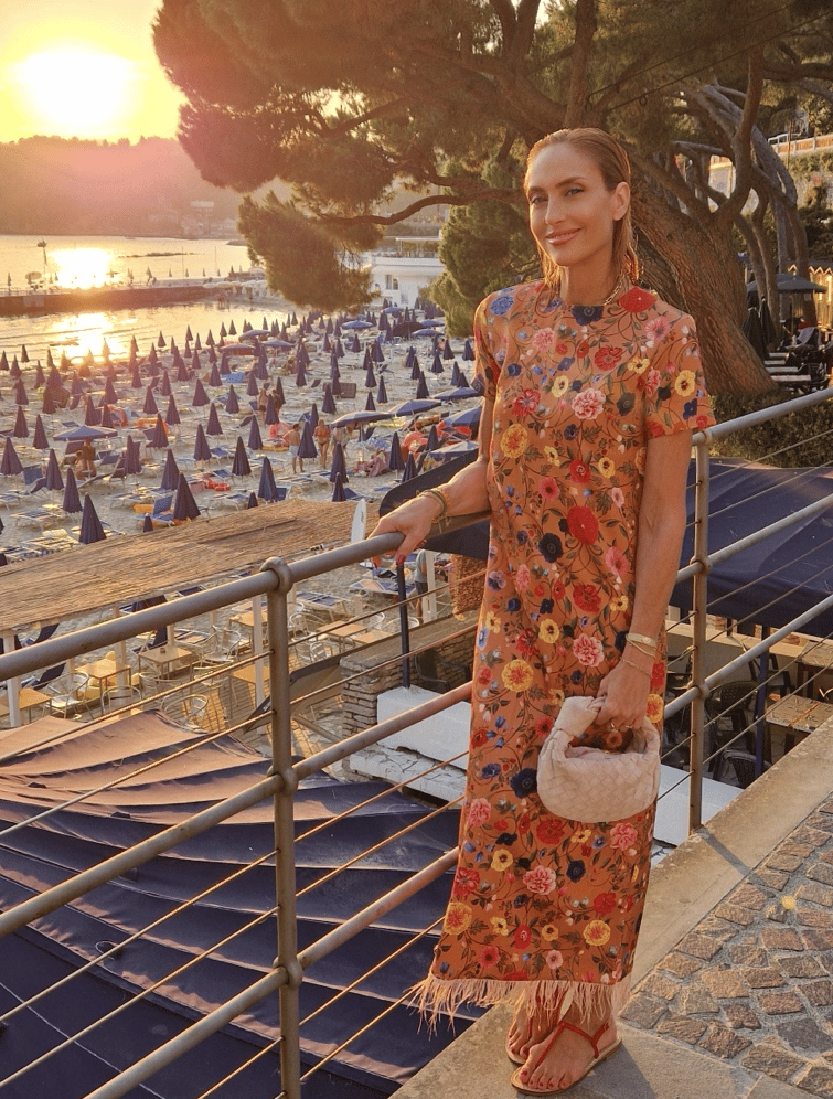 Woman in floral dress at sunset on beach in Santa Margherita Ligure, Italy.