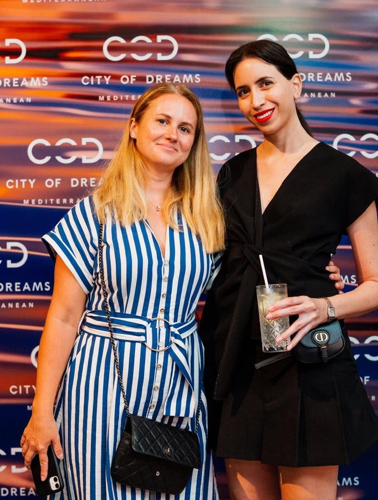 two women standing next to each other in front of a city backdrop