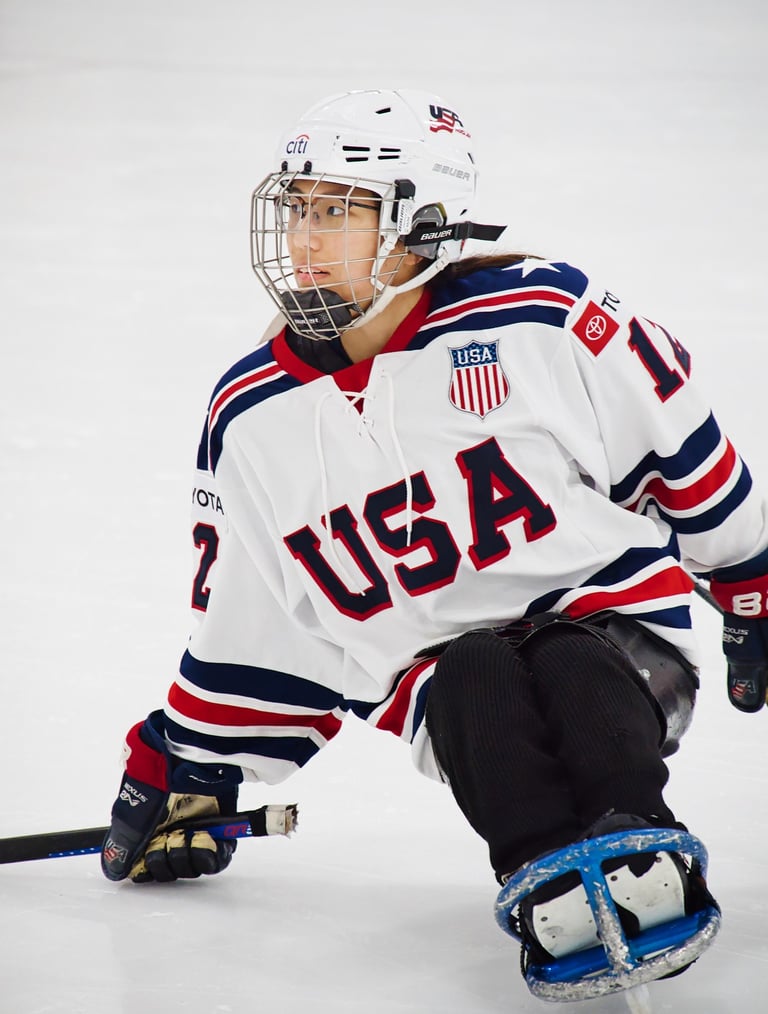 a sled hockey player in a white USA jersey and a hockey helmet