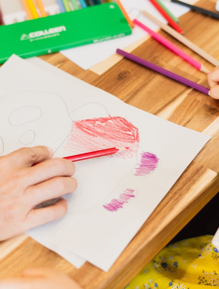 a child's hand is drawing a heart with colored  at Kinntorpencils
