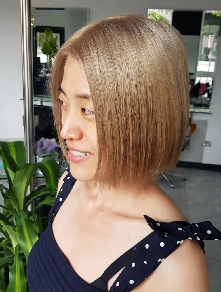 Woman with a stylish ash blonde bob haircut and straight hair at a professional salon.