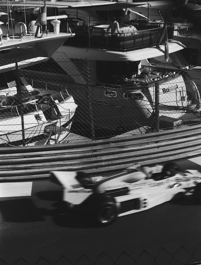 a race car racing down the track with a boat in the background in Monaco