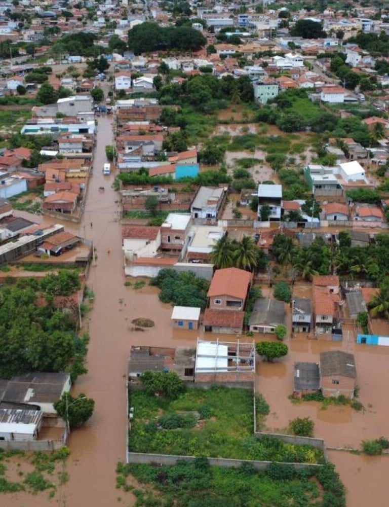 Enchentes e destruição urbana causadas por chuvas intensas em Minas Gerais, com ruas alagadas, pavim