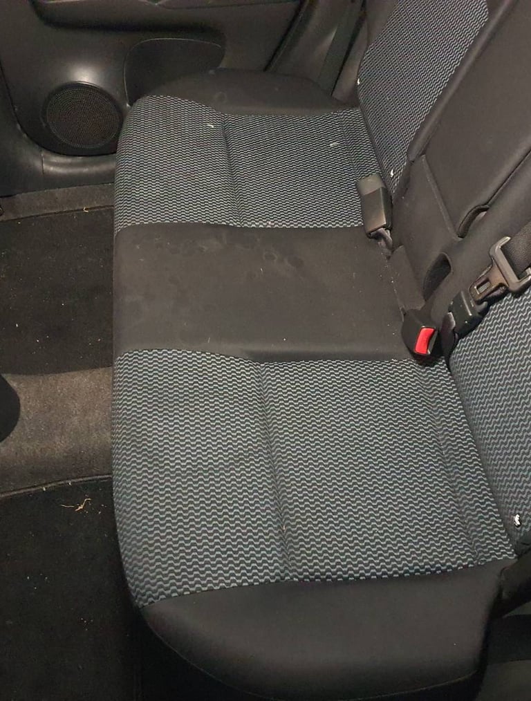 Tylna kanapa samochodu z plamami przed praniem.