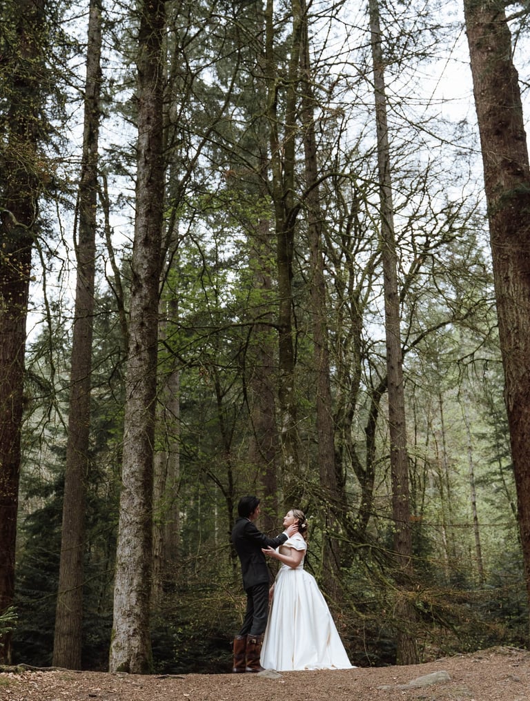 a bride and groom standing in a forest