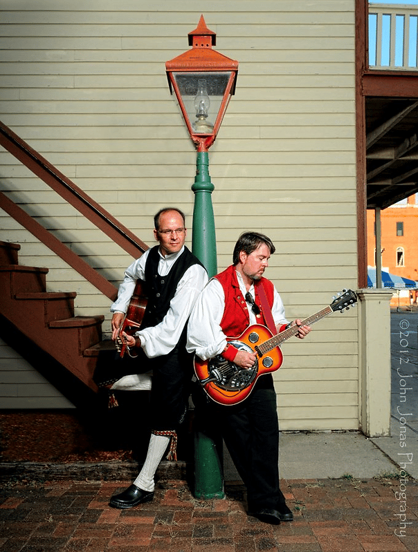 two men hold guitars near a lightest