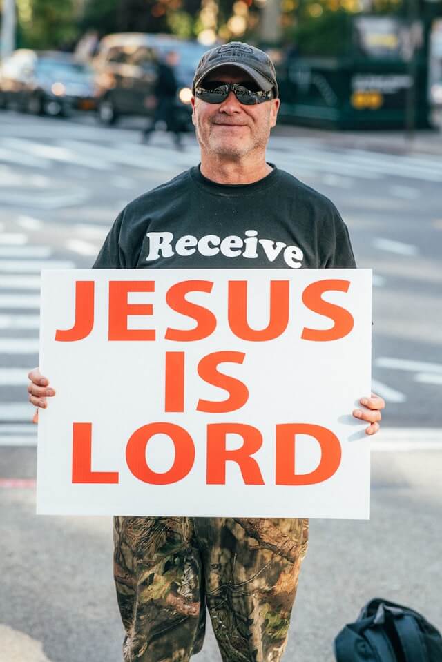 a man holding a sign that says jesus is lord