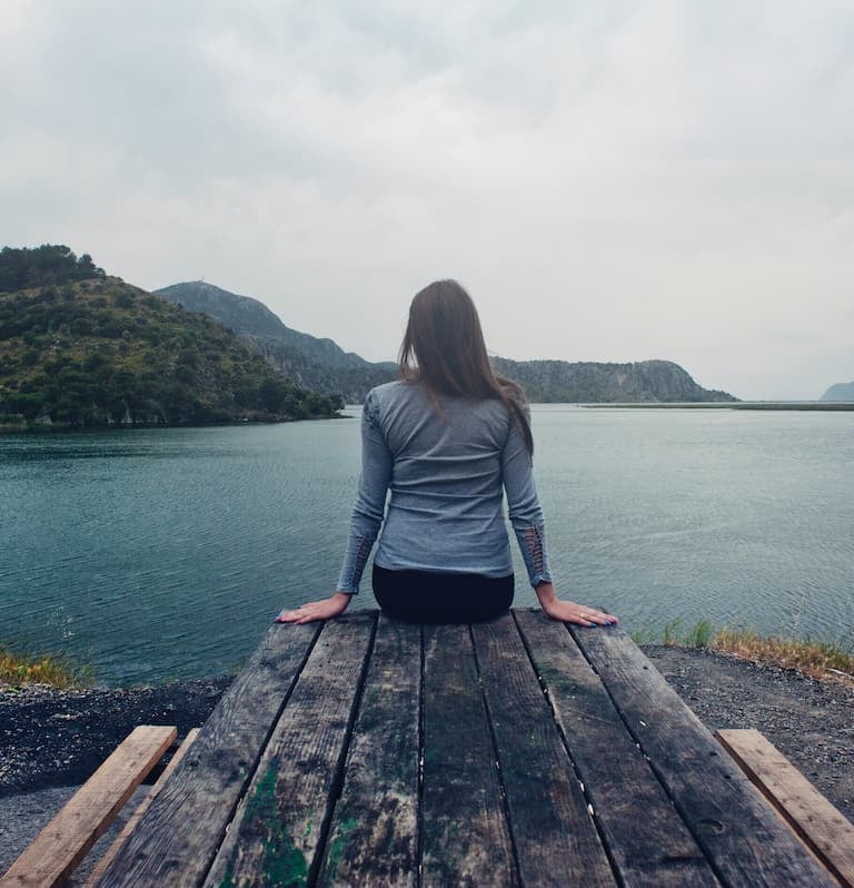 femme seule face à un lac moment calme méditation