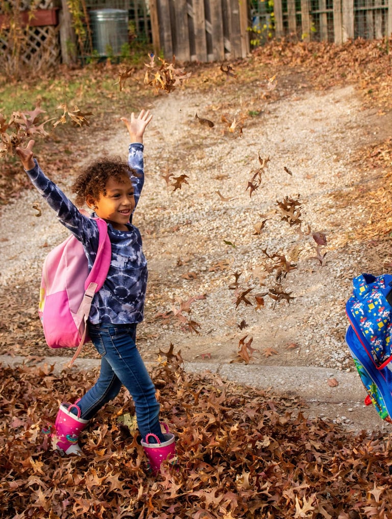 Young girl walking to Access Arts throwing leaves in the air.