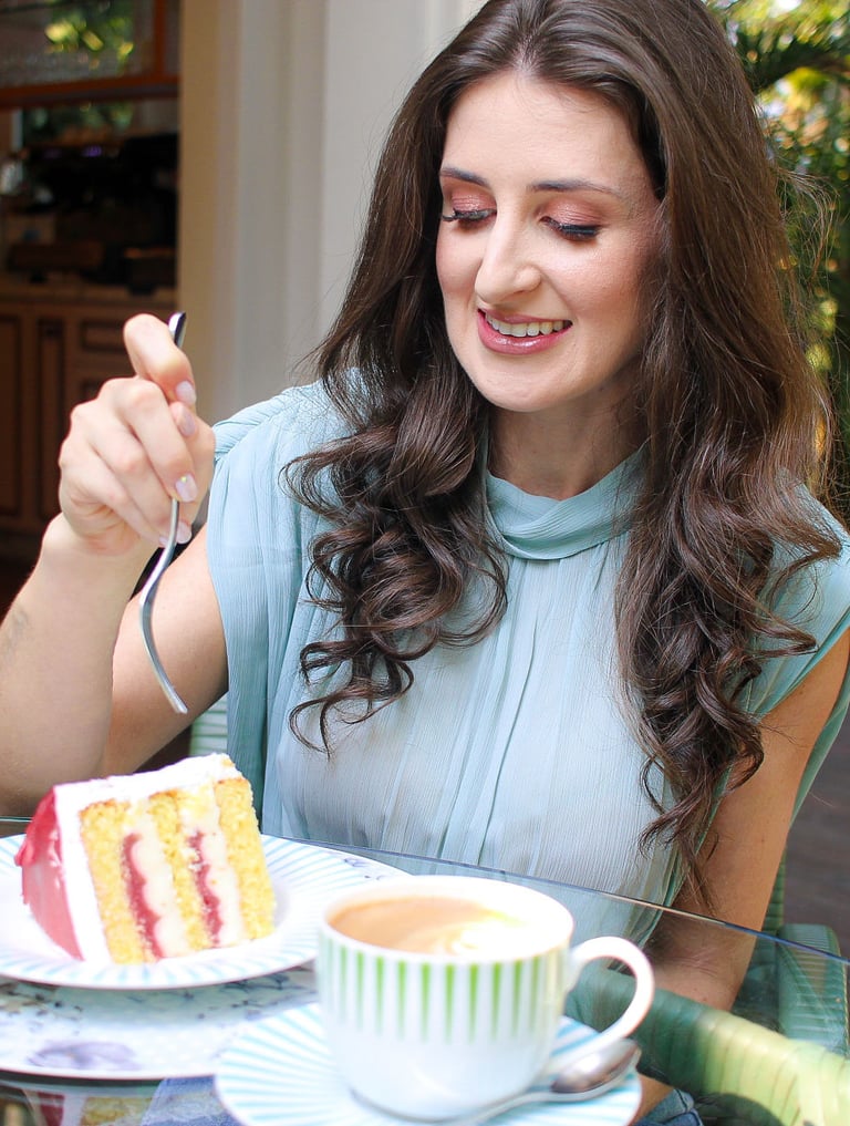 Foto da nutricionista em Jaraguá do Sul, Kamila Kuester, sorrindo enquanto come uma fatia de bolo.
