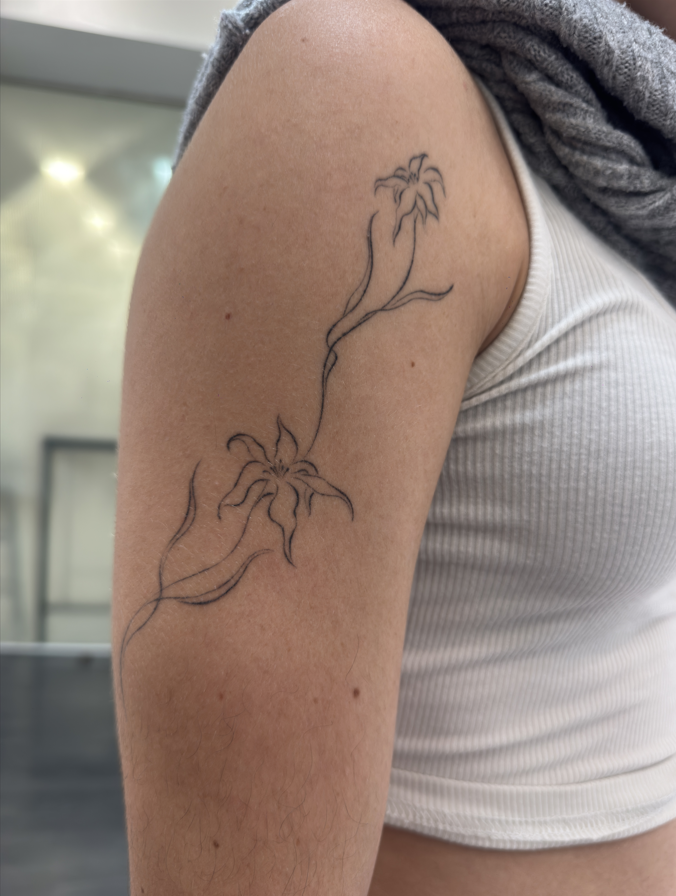 Fine line lily flower tattoo on shoulder – Sinkply Zürich