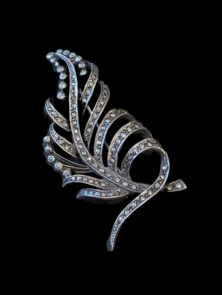 a silver and diamond feather brooch