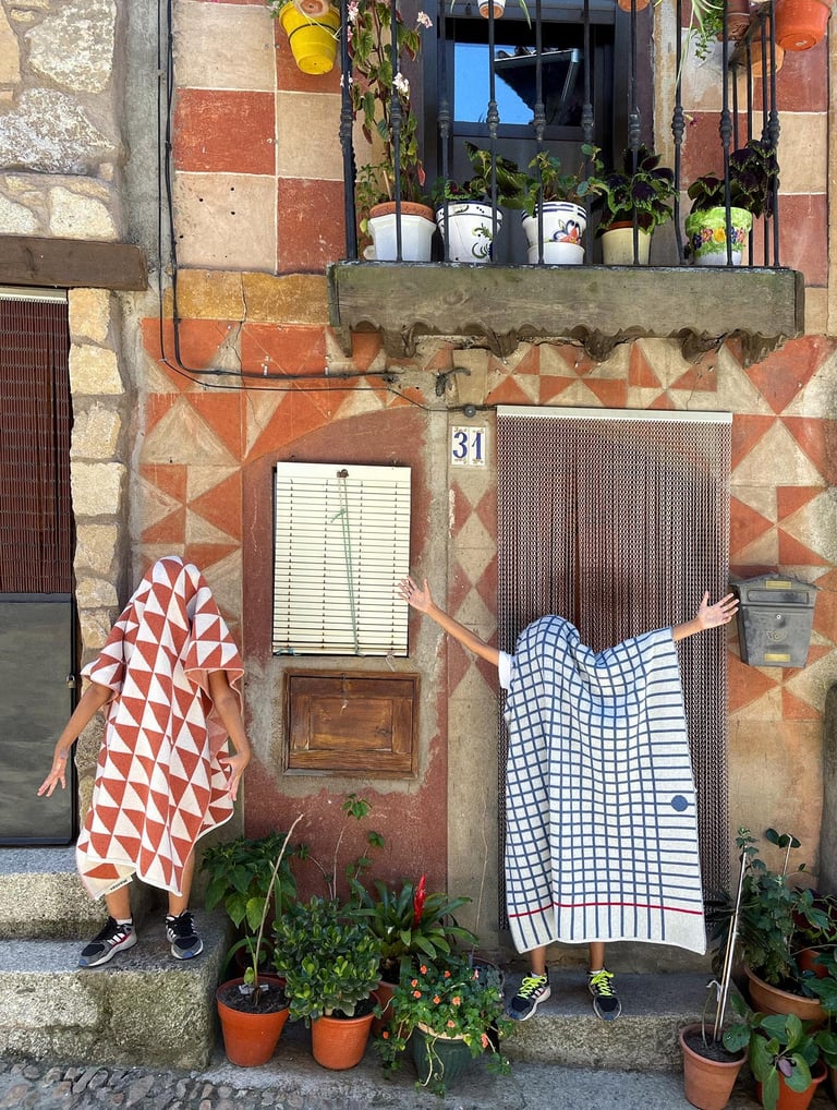 two people covered by blankets standing in front of a building