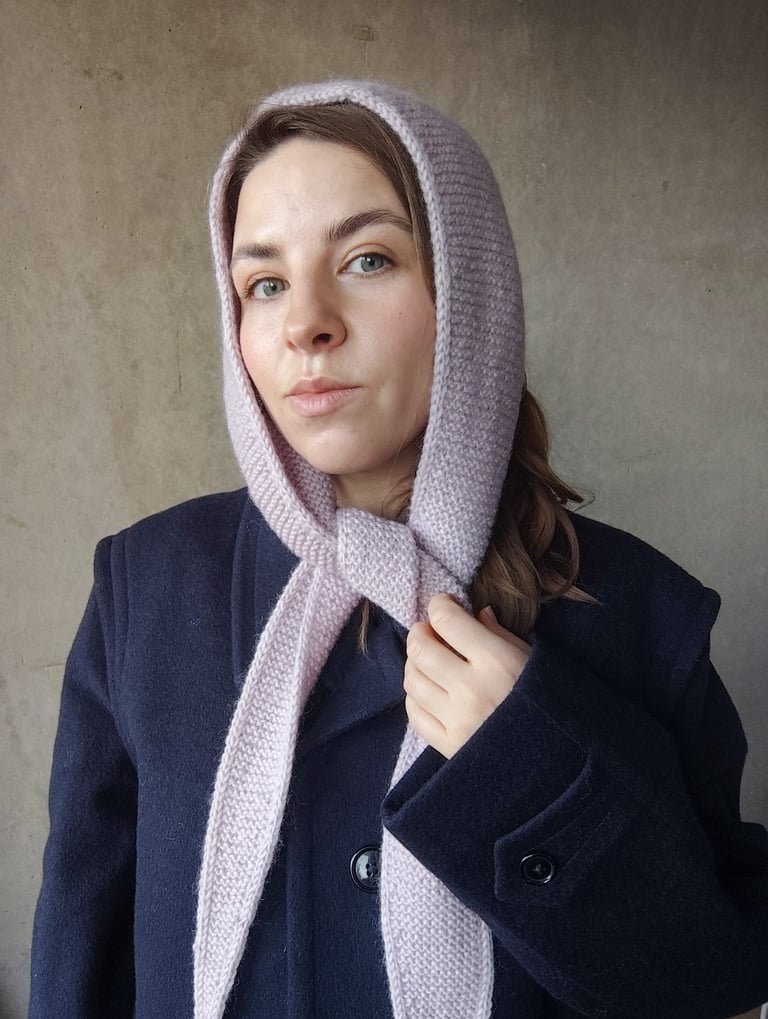 kobieta z wełnianym szalem na głowie na tle szarej ściany