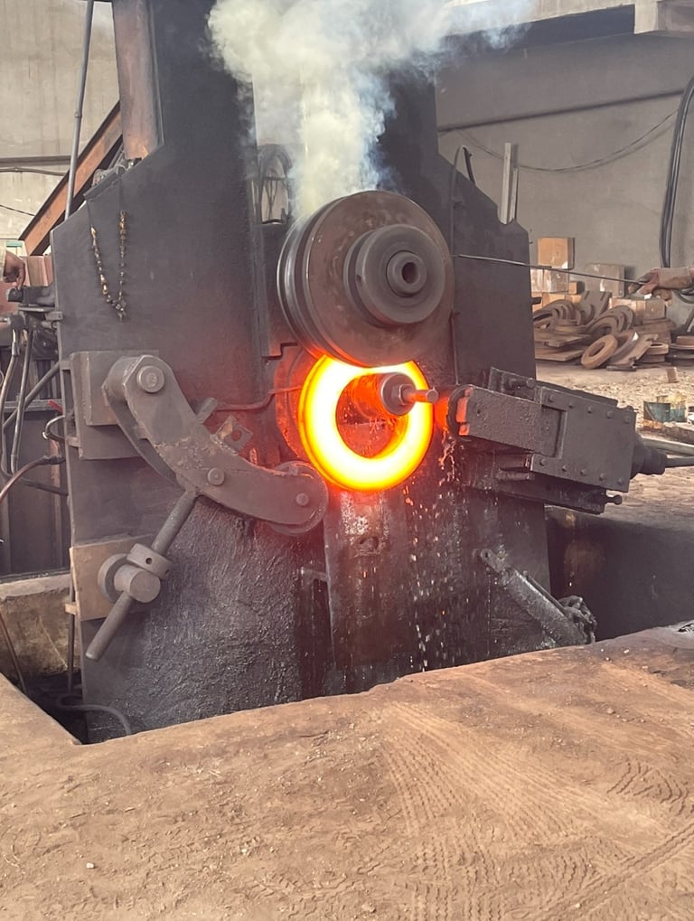 Industrial ring rolling machine shaping a glowing red-hot metal ring in a steel forging factory.