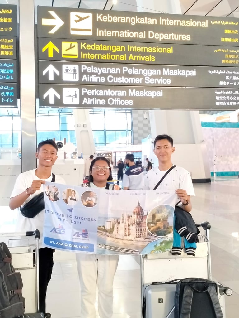 crew posing with AKA banner at an international airport terminal departures sign.