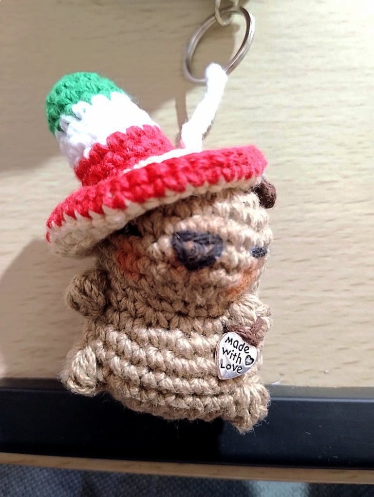 Llavero de capibara marrón tejido a mano en crochet, con un sombrero mexicano verde, blanco y rojo.