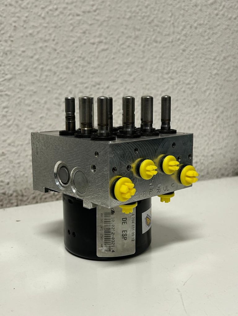 FOTO DEL COSTADO BOMBA HIDRAULICA DE ABS DESTAPADO Y RECIEN REPARADO CON TAPONES AMARILLOS DE CLAIRICAR EN LOS CANALES