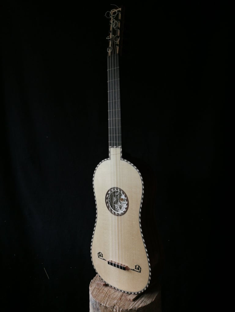 Handcrafted baroque guitar with intricate rosette and decorative purfling on a black background.