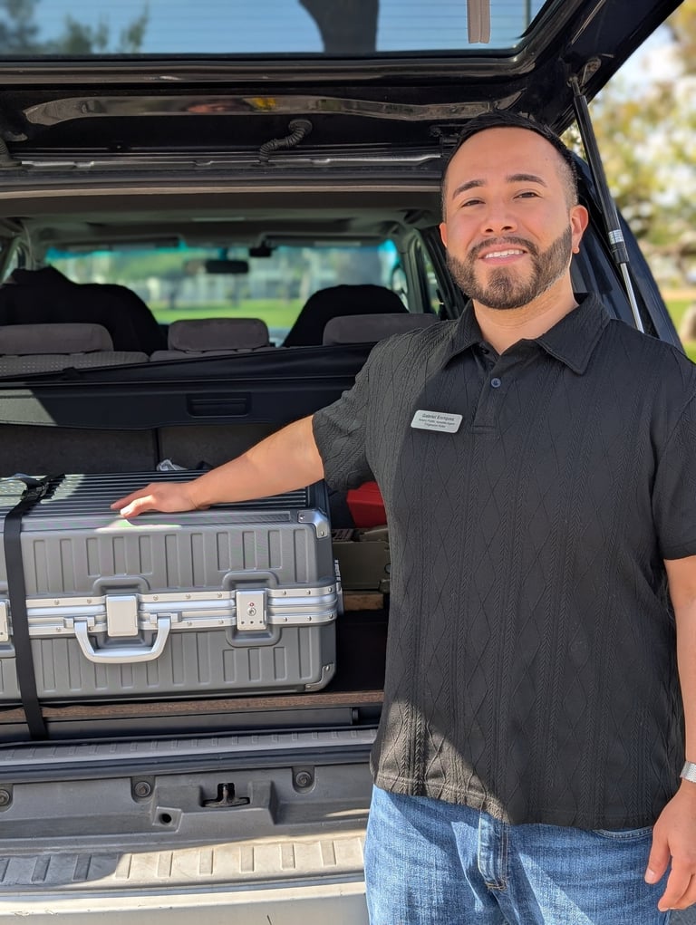 Professional event coordinator loading a silver equipment flight case into an SUV trunk.