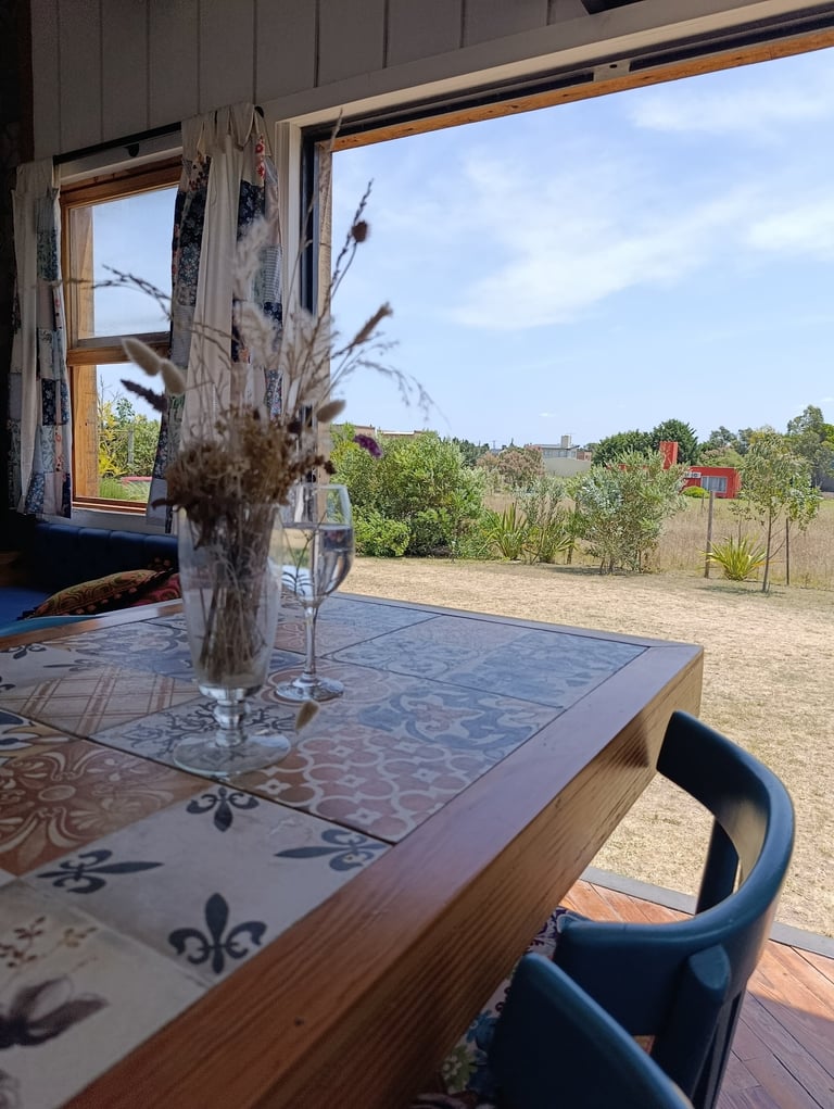 Comedor de la tiny house Siestas y Olas con mesa de diseño y vistas despejadas al parque