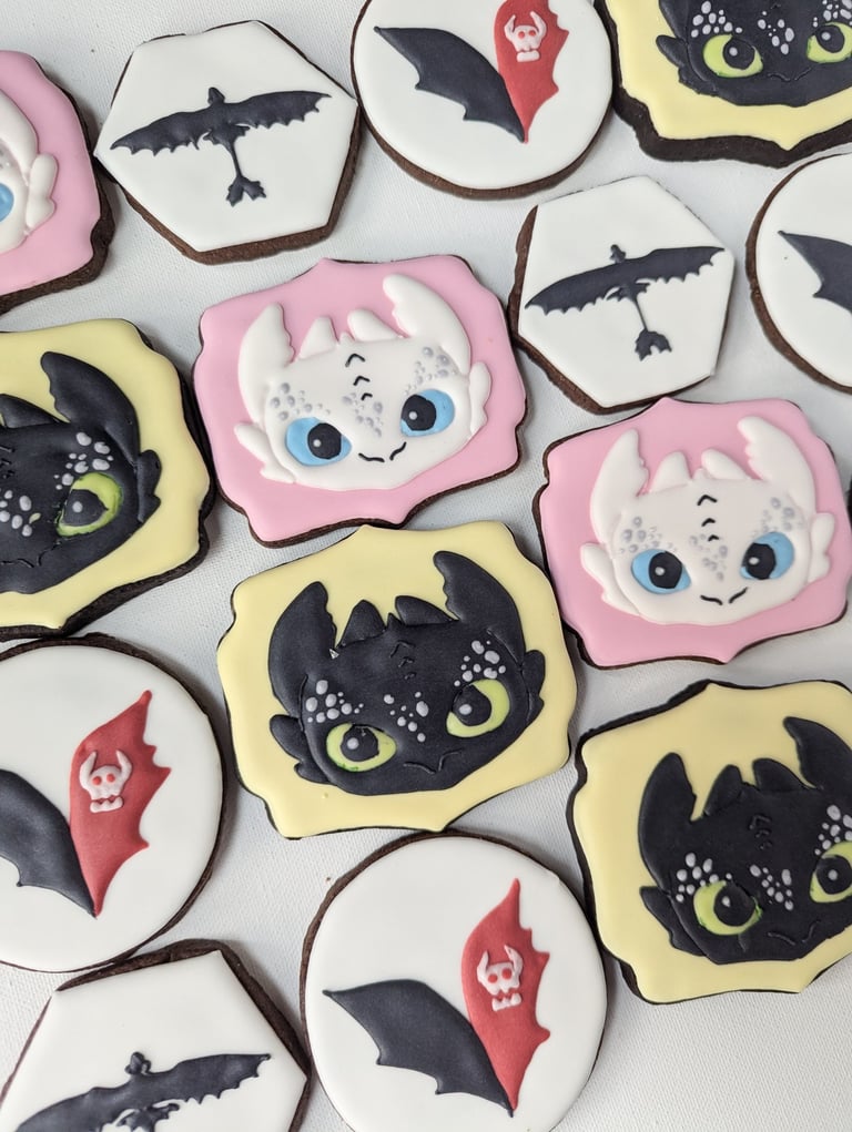 Cookies with yellow or pink icing, designed with How to Train Your Dragon characters