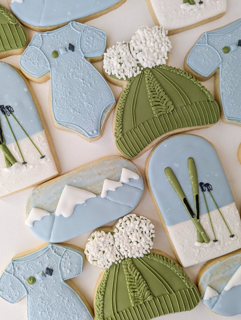 Cookies of onesies, hats, skis, and mountains for a baby shower