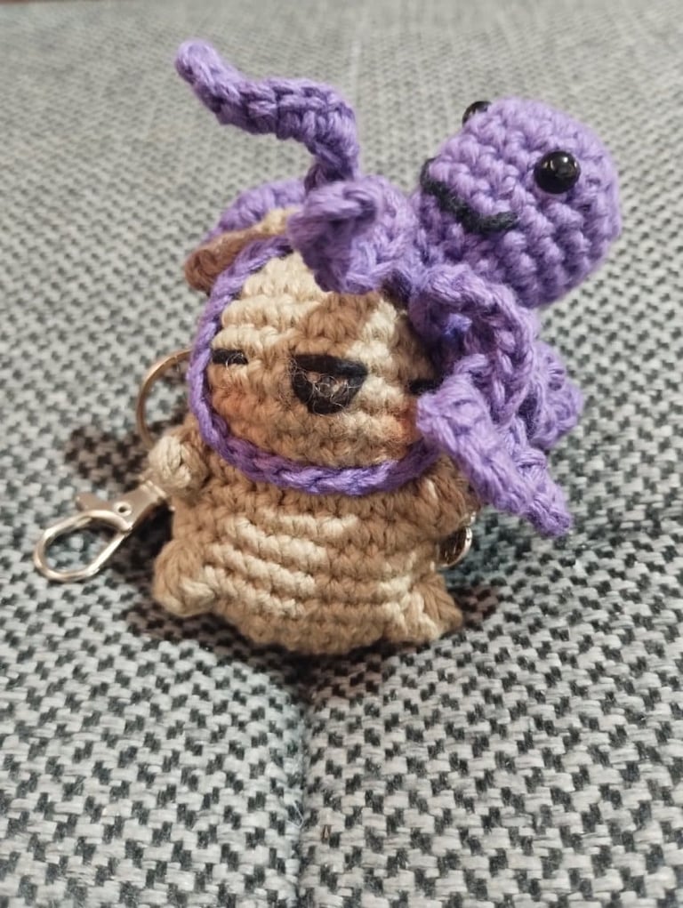 Llavero de amigurumi hecho a mano, tejido a crochet, con un capibara color canela y un pulpo morado.