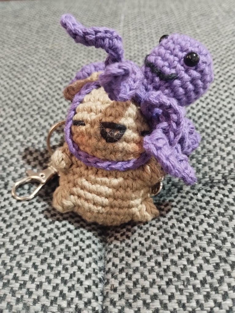 Llavero de amigurumi hecho a mano, tejido a crochet, con un capibara color canela y un pulpo morado.