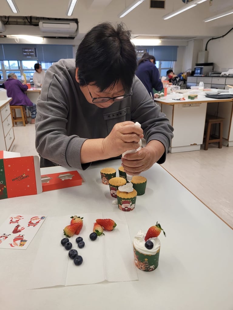 「社福機構長者烘焙班：長者專注練習聖誕 Cupcake 唧花裝飾，透過手作活動訓練手部肌肉並建立自信。」