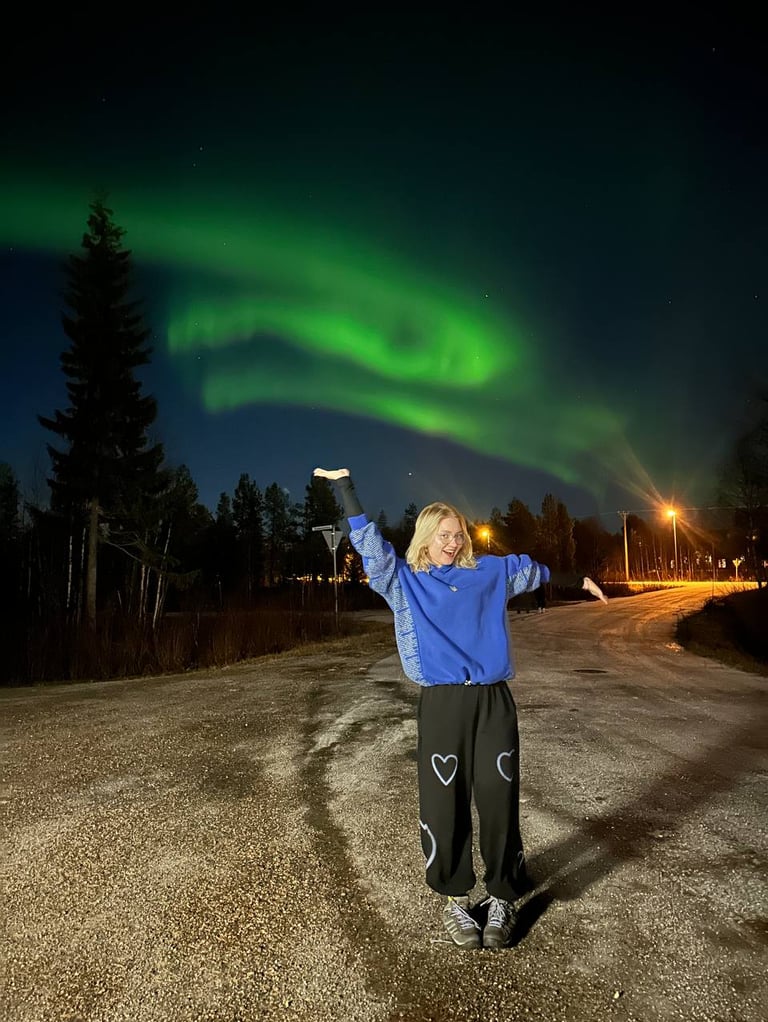 a woman standing under the northern lights
