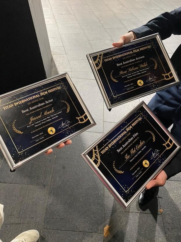 three people holding up plaques with their awards