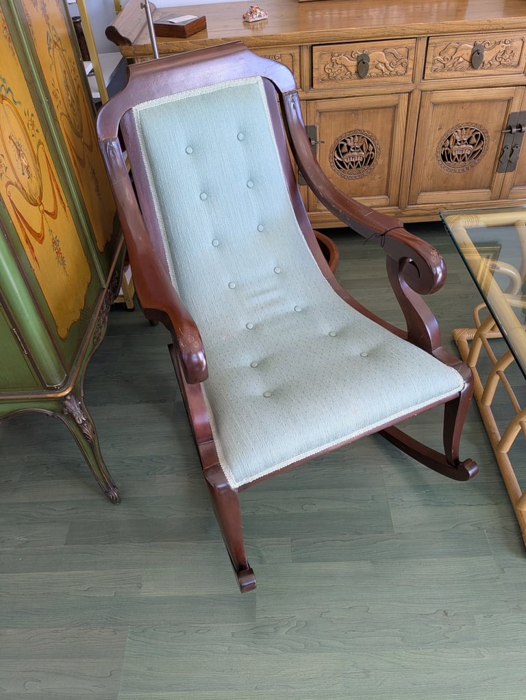 Vintage mahogany rocking chair with a tufted sage green upholstered seat and backrest.
