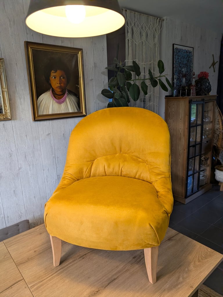 Yellow velvet accent chair with wooden legs in a stylish living room interior.