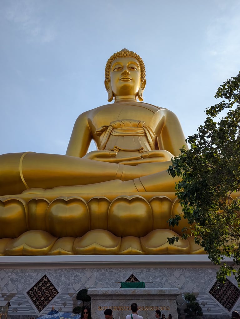A giant golden Buddha statue sitting in a meditative pose at a Buddhist temple in Thailand.