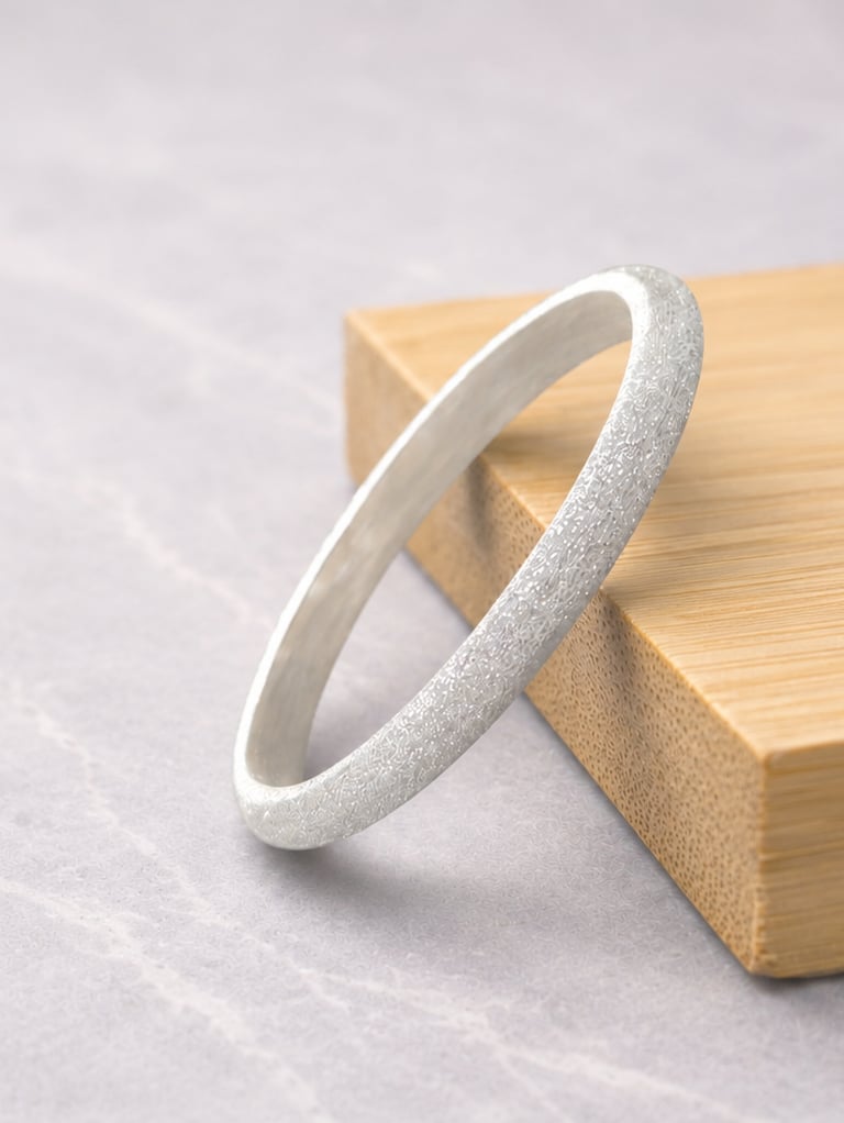 Elegant 999 fine silver ring with a frosted finish resting on a bamboo block over marble background