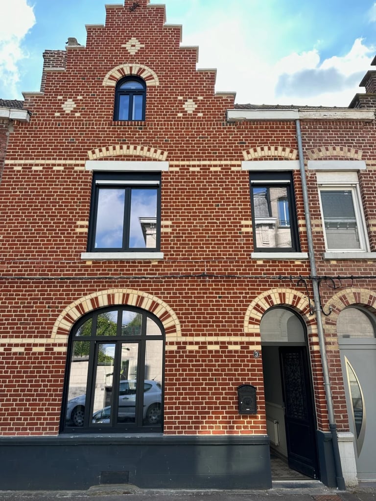 Maison en briques rouge avec fenêtres en aluminium noir
