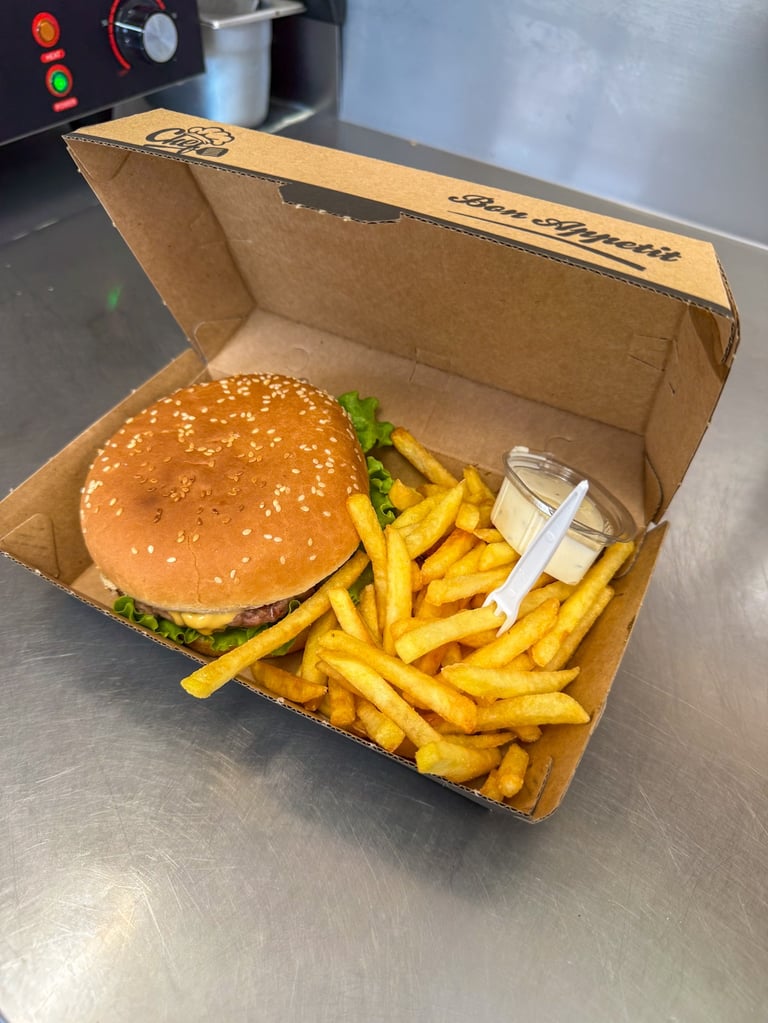 Un cheeseburger  accompagné de frites dorées et avec sauce , dans une boîte à importer