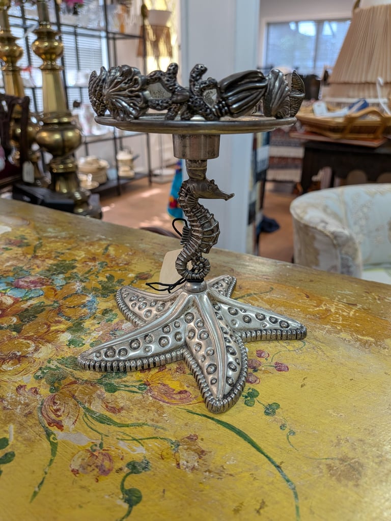Vintage coastal candle holder with a seahorse stem and starfish base on a floral table.